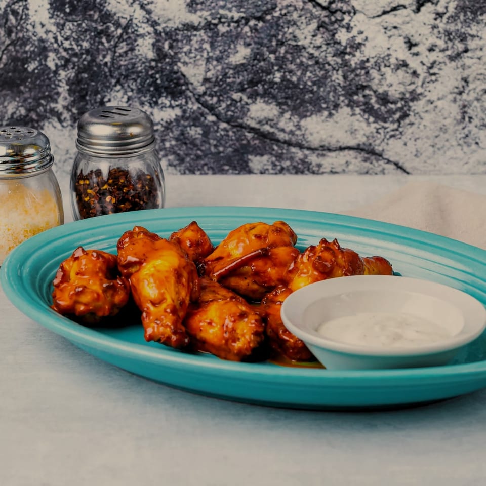 A plate of SilverLake Pizza & Pasta's chicken wings with dipping sauce, parmesan, and chili flakes.