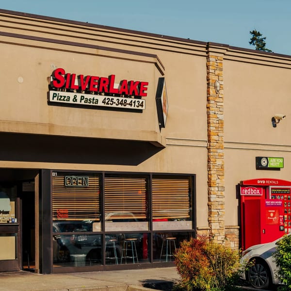 Exterior of SilverLake Pizza & Pasta with a red sign, large windows, and a Redbox kiosk.
