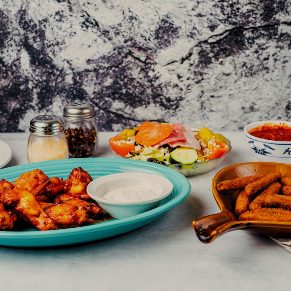 A spread of SilverLake Pizza & Pasta dishes: chicken wings, salad, mozzarella sticks, and marinara sauce.